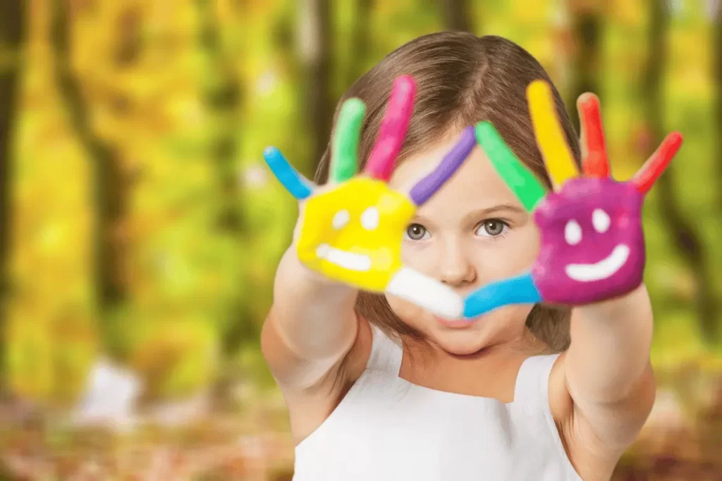 una bambina mostra le mani colorate