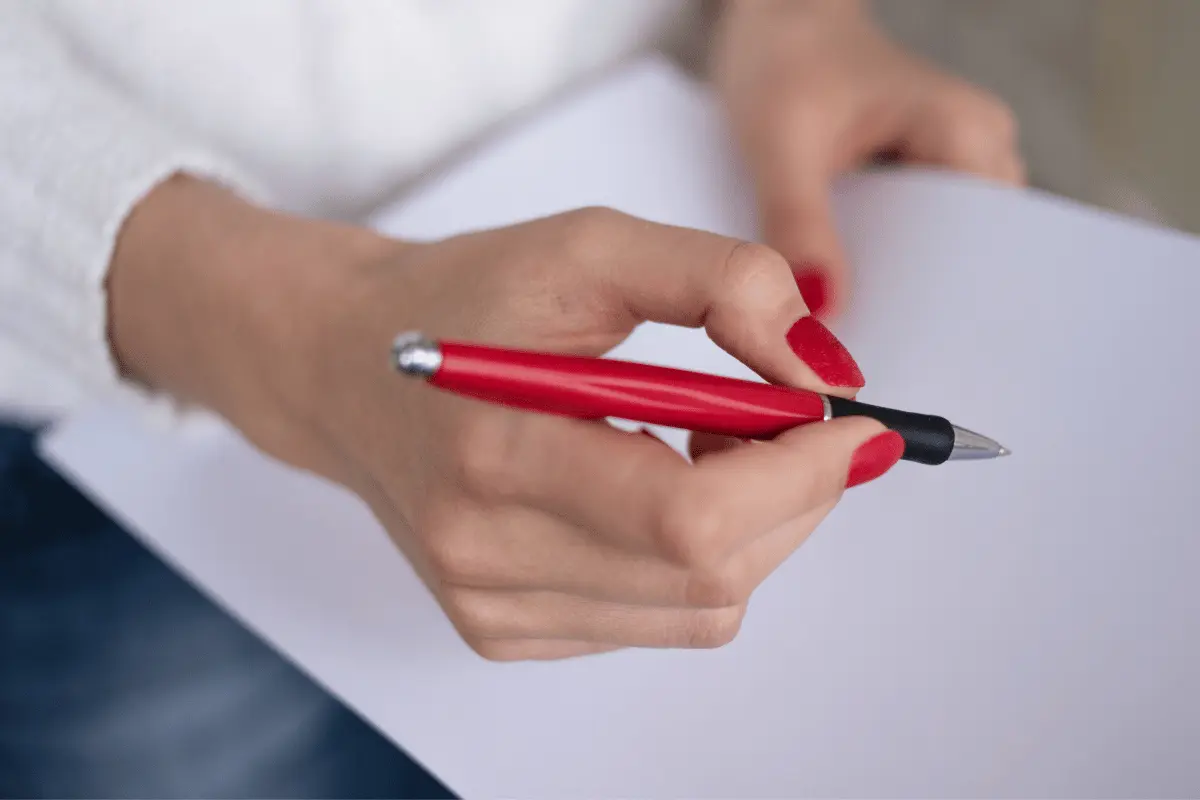 docente con in mano una penna e un foglio si appresta a scrivere un'autocertificazione