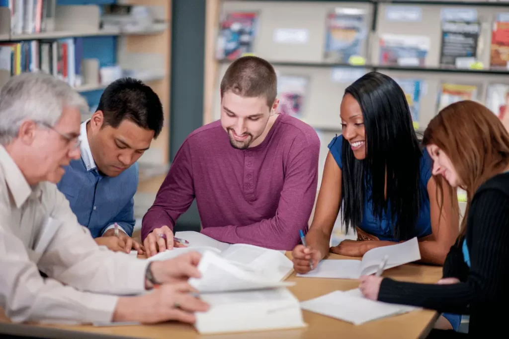 insegnanti di nazionalità diversa seduti a una scrivania con libri