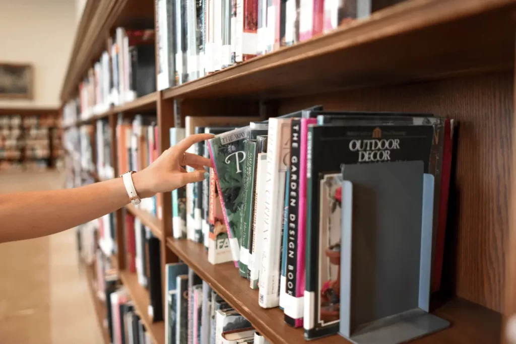 una ragazza prende un libro dallo scaffale di una biblioteca