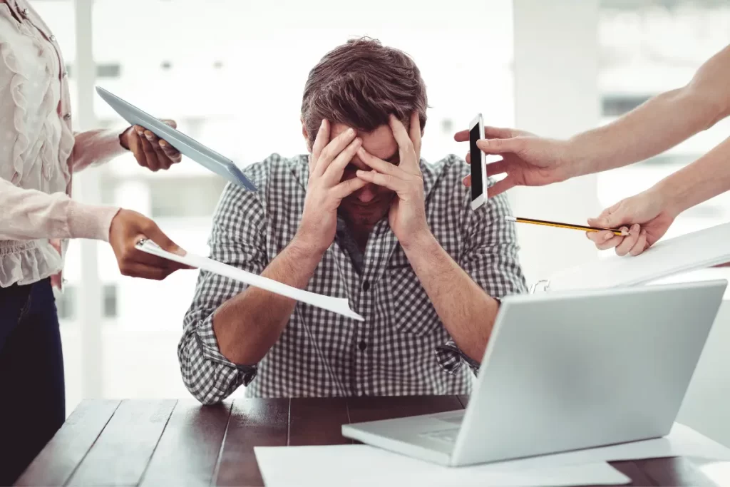 professore davanti ad un pc con le mani in faccia, incalzato da diversi colleghi