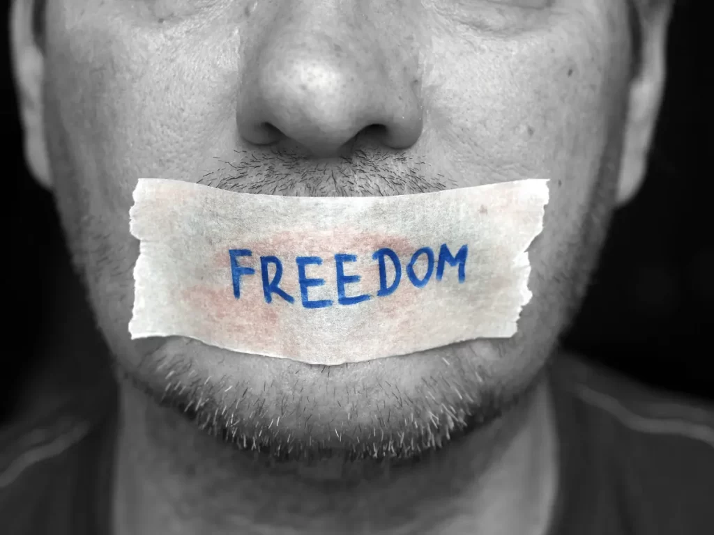 un uomo con un cerotto sulla bocca con la scritta "Freedom"