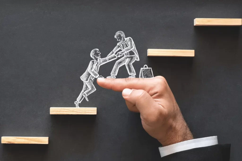 disegno su una lavagna di un uomo che aiuta un altro a salire un gradino